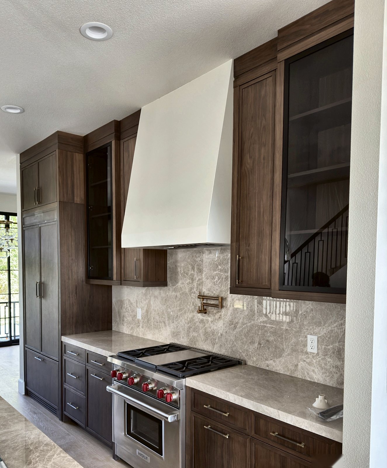 Walnut kitchen with white plaster hood and stone backsplash